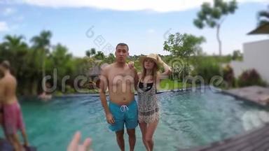 年轻可爱的夫妇在热带度假别墅拍照并掉进游泳池。